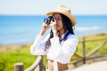 A Young Woman Joyfully Capturing Beautiful Summer Moments at the Picturesque Beach