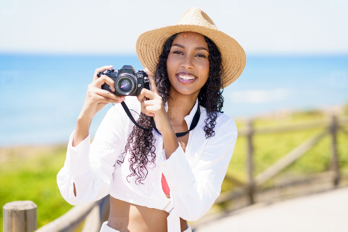 A Joyful Woman Taking Pictures with Her Camera on the Beautiful Beach on a Sunny Day