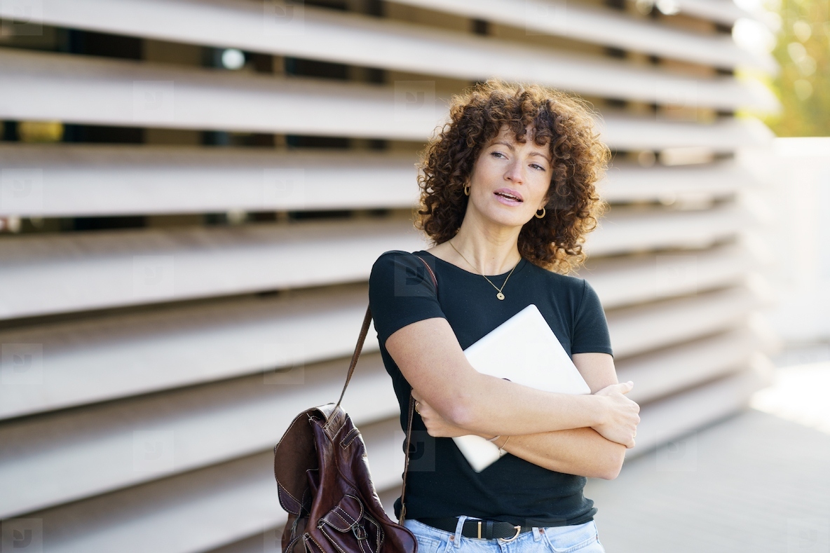 A Young Woman with Beautiful Curly Hair is Standing Confidently in a Vibrant Outdoor Setting