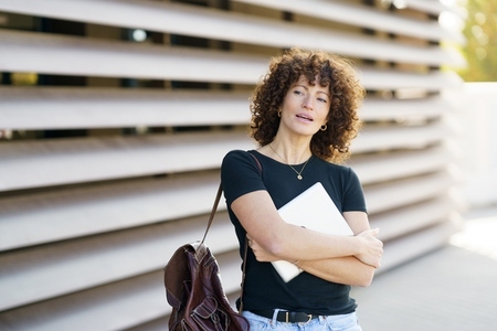 A Young Woman with Beautiful Curly Hair is Standing Confidently in a Vibrant Outdoor Setting A Young Woman with Beautiful Curly Hair is Standing Confidently in a Vibrant Outdoor Setting