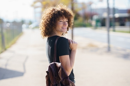 A Young Woman with Gorgeous Beautiful Curly Hair Happily Strolling and Enjoying the Outdoors A Young Woman with Gorgeous Beautiful Curly Hair Happily Strolling and Enjoying the Outdoors