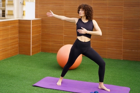 A woman is practicing various yoga poses outdoors while using a fitness ball for support
