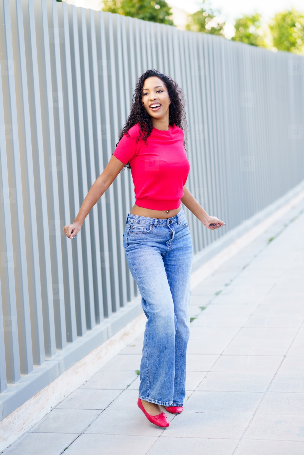 A Joyful Woman Dancing in a Vibrant and Colorful Outfit on a Bustling City Street