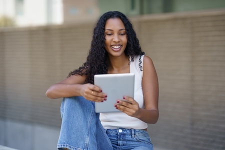 A Young Woman Engaged with a Tablet in a Bustling Urban Setting During Daylight Hours A Young Woman Engaged with a Tablet in a Bustling Urban Setting During Daylight Hours