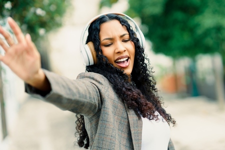 A Joyful Woman Dancing Freely with Headphones on in a Lively Urban Setting Filled with Energy A Joyful Woman Dancing Freely with Headphones on in a Lively Urban Setting Filled with Energy
