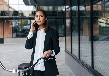 Young stylish woman in black formal clothes with bicycle