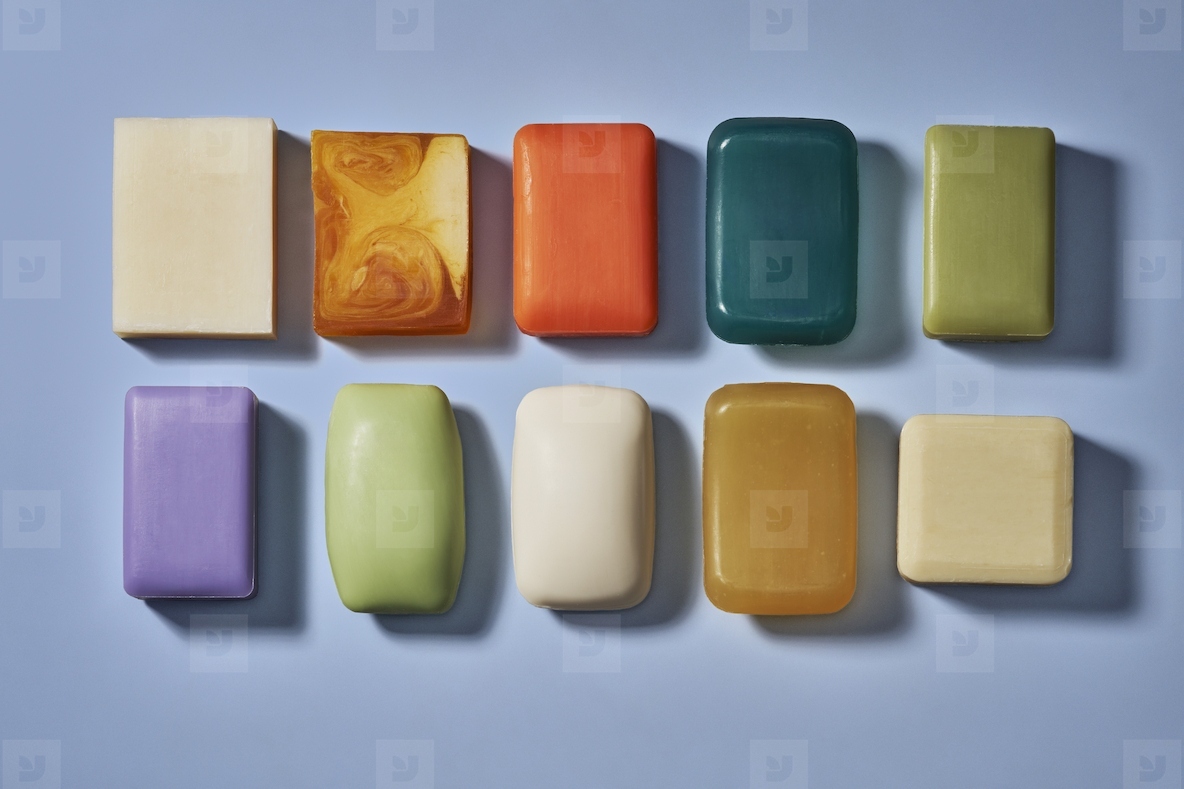 Flat lay still life rows of various multicolored homemade soap bars on blue background