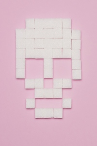 Still life conceptual shot of white sugar cubes forming skull on pink background