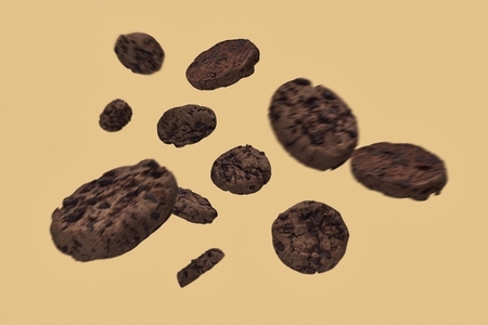 Blurred chocolate chip cookies falling against beige background Blurred chocolate chip cookies falling against beige background