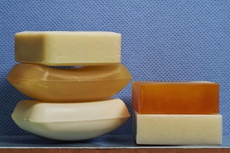 Still life of various homemade soap bars against textured blue background