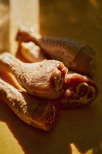 Still life sunlight over raw chicken legs on yellow plate