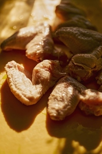 Still life of sunlight over raw chicken wings on yellow surface