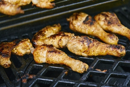 Chicken drumsticks grilling on barbecue grill