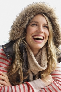 Portrait of happy carefree woman in fur lined hood laughing with mouth open