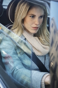 View of beautiful blond woman in scarf driving car from window