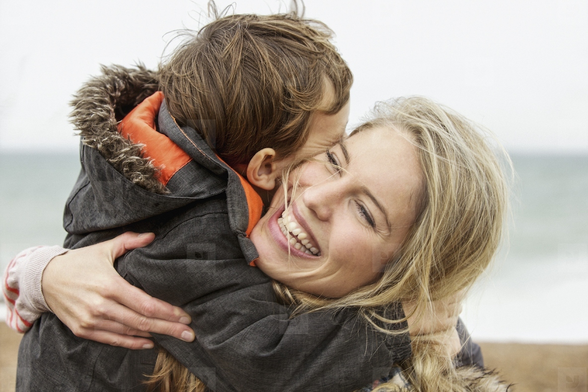 Happy carefree mother hugging son on beach