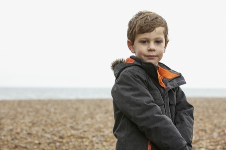 Portrait of cute boy in jacket on rocky winter beach