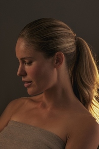 Studio portrait of beautiful blond woman with ponytail and bare shoulders looking down