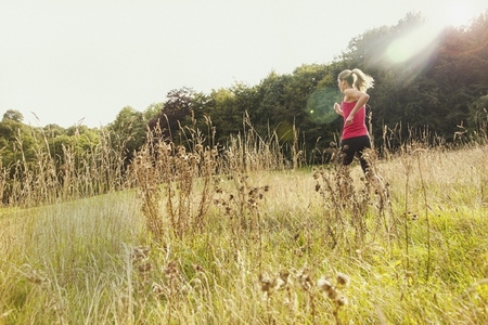 Woman jogging in sunny rural summer field