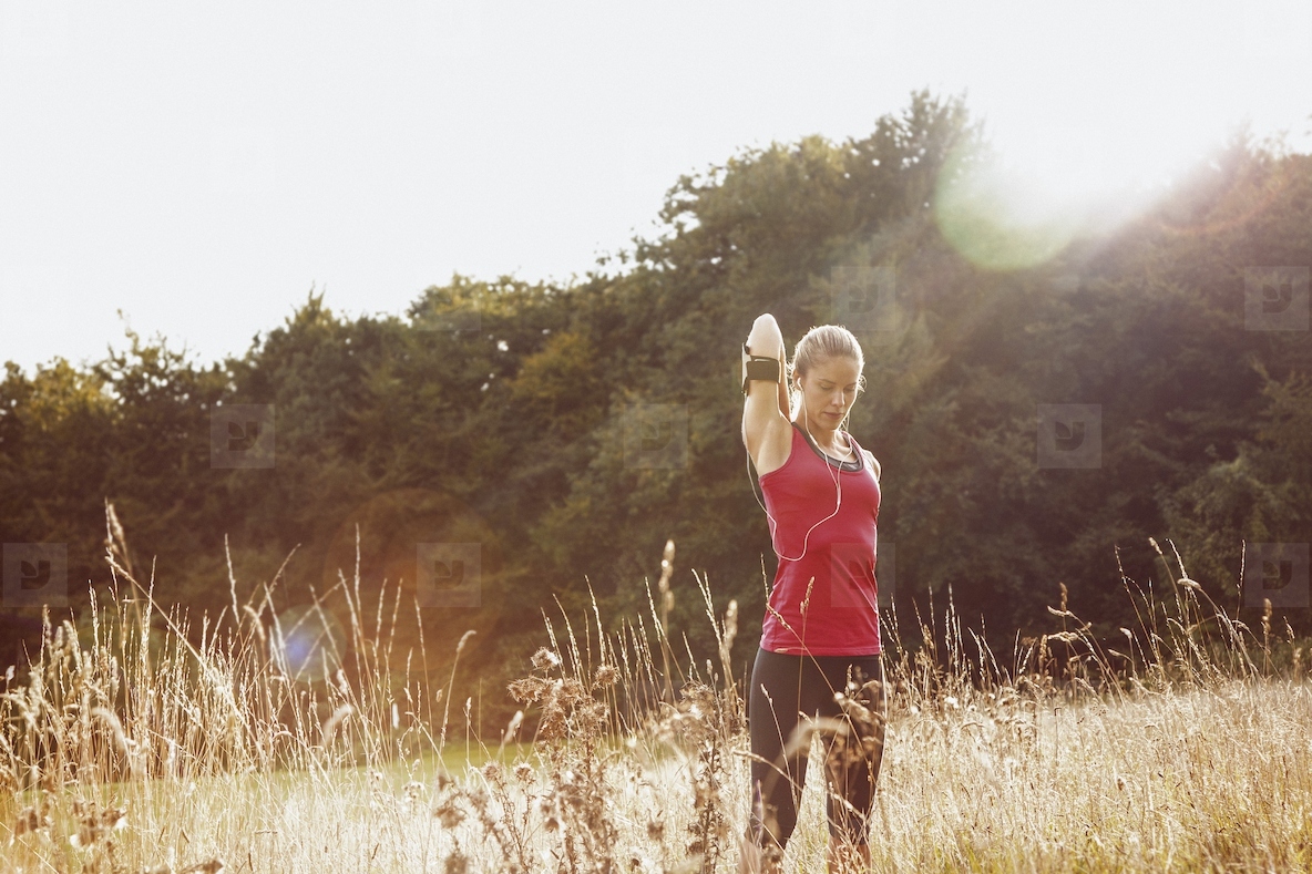 Female runner stretching arm in sunny