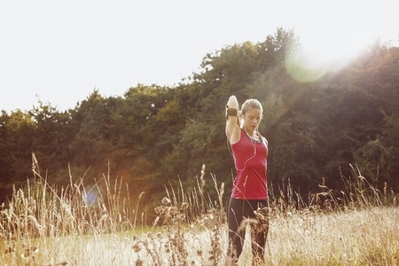 Female runner stretching arm in sunny Female runner stretching arm in sunny