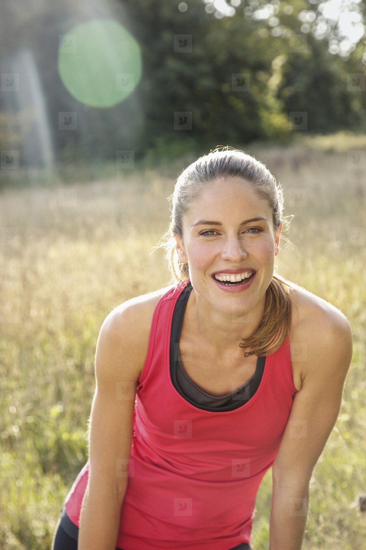 Portrait of happy beautiful blond female runner in sunny park