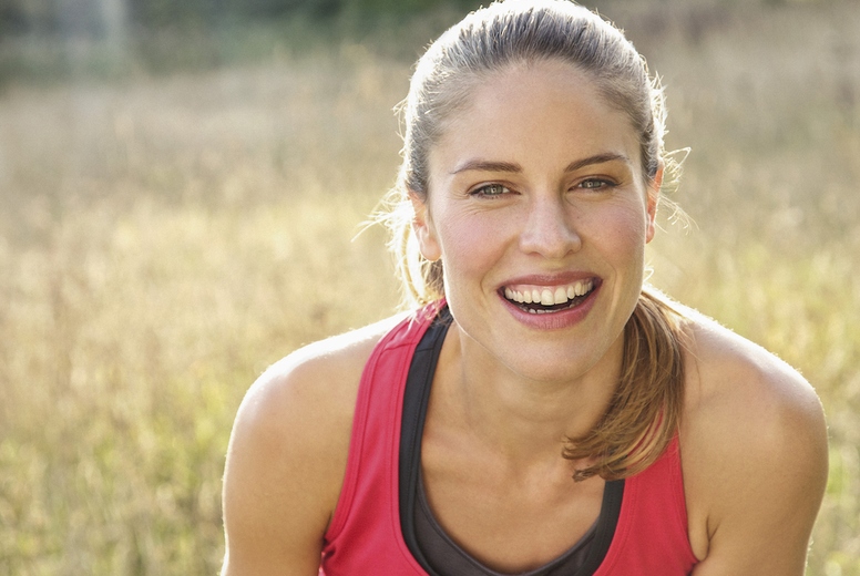 Portrait of happy beautiful blond female runner in sunny park