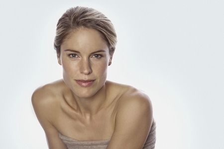 Studio portrait of beautiful blond woman with bare shoulders against white background