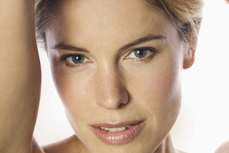 Close up studio portrait of beautiful blond woman with bare shoulders and arms raised