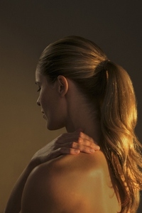 Studio portrait of golden light over beautiful blond woman with ponytail and bare shoulders