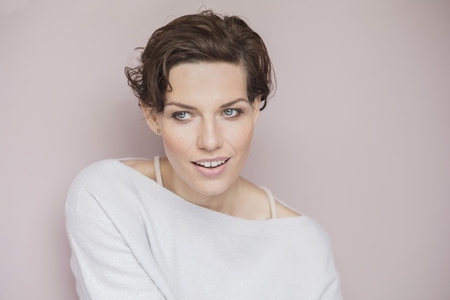 Studio portrait of beautiful brunette woman with blue eyes looking away on pink background
