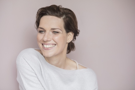 Studio portrait of happy beautiful young woman with short brown hair smiling and looking away