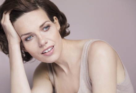 Portrait of beautiful young brunette woman with blue eyes leaning and looking away with hand in hair
