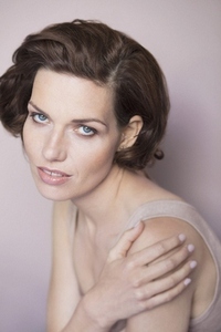 Studio portrait of beautiful young woman with blue eyes and brown hair touching shoulder