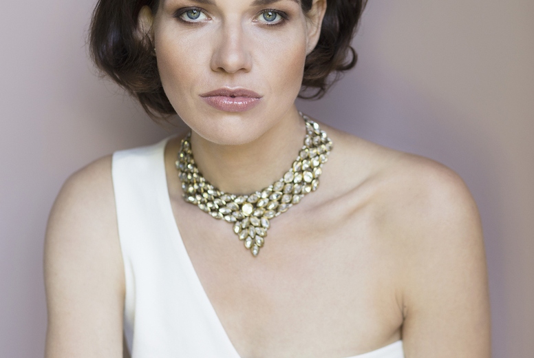 Studio portrait of confident elegant woman in fashionable white dress and necklace