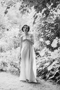Portrait of beautiful tall woman with short hair wrapped in gauze sheet in summer garden Portrait of beautiful tall woman with short hair wrapped in gauze sheet in summer garden