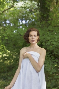 Portrait of beautiful woman with short brown hair and bare shoulders holding blanket over her body Portrait of beautiful woman with short brown hair and bare shoulders holding blanket over her body