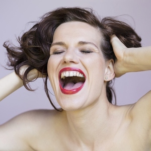 Close up studio portrait of beautiful carefree young brunette woman with bare shoulders laughing