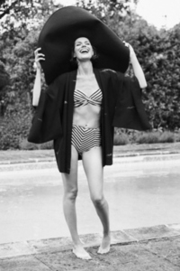 Black and white portrait of beautiful tall carefree young woman in bikini and large sun hat