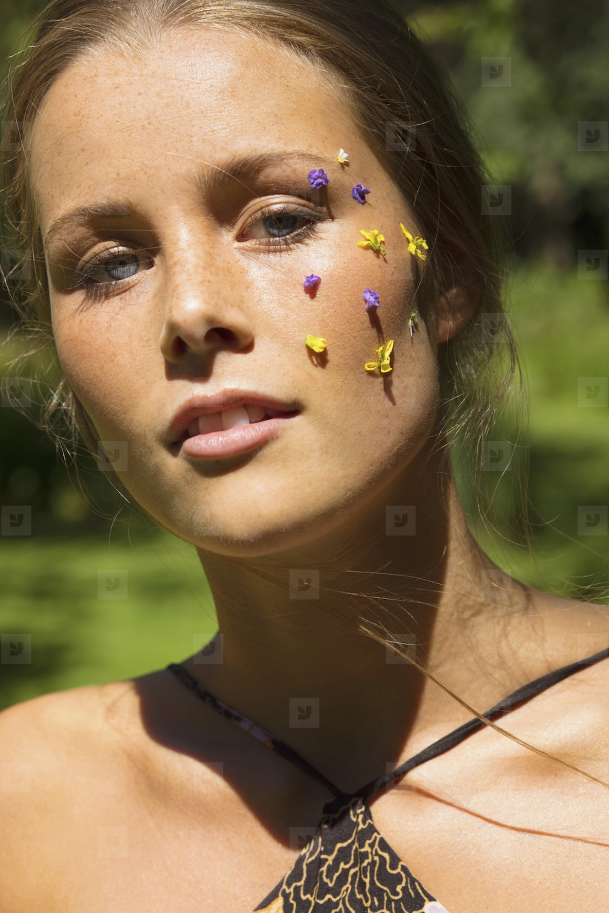 Close up portrait of beautiful young woman with purple and yellow flower petals on face