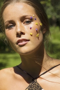Close up portrait of beautiful young woman with purple and yellow flower petals on face