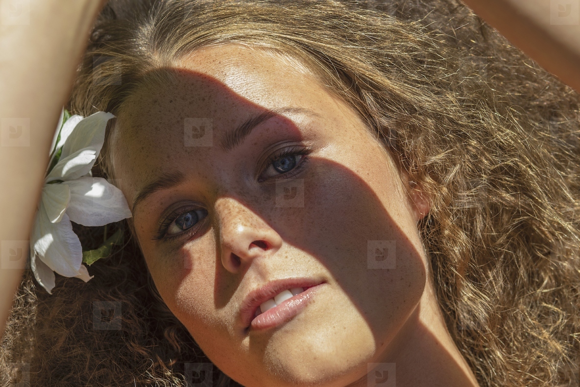 Close up portrait of beautiful young woman shading eyes in sunlight