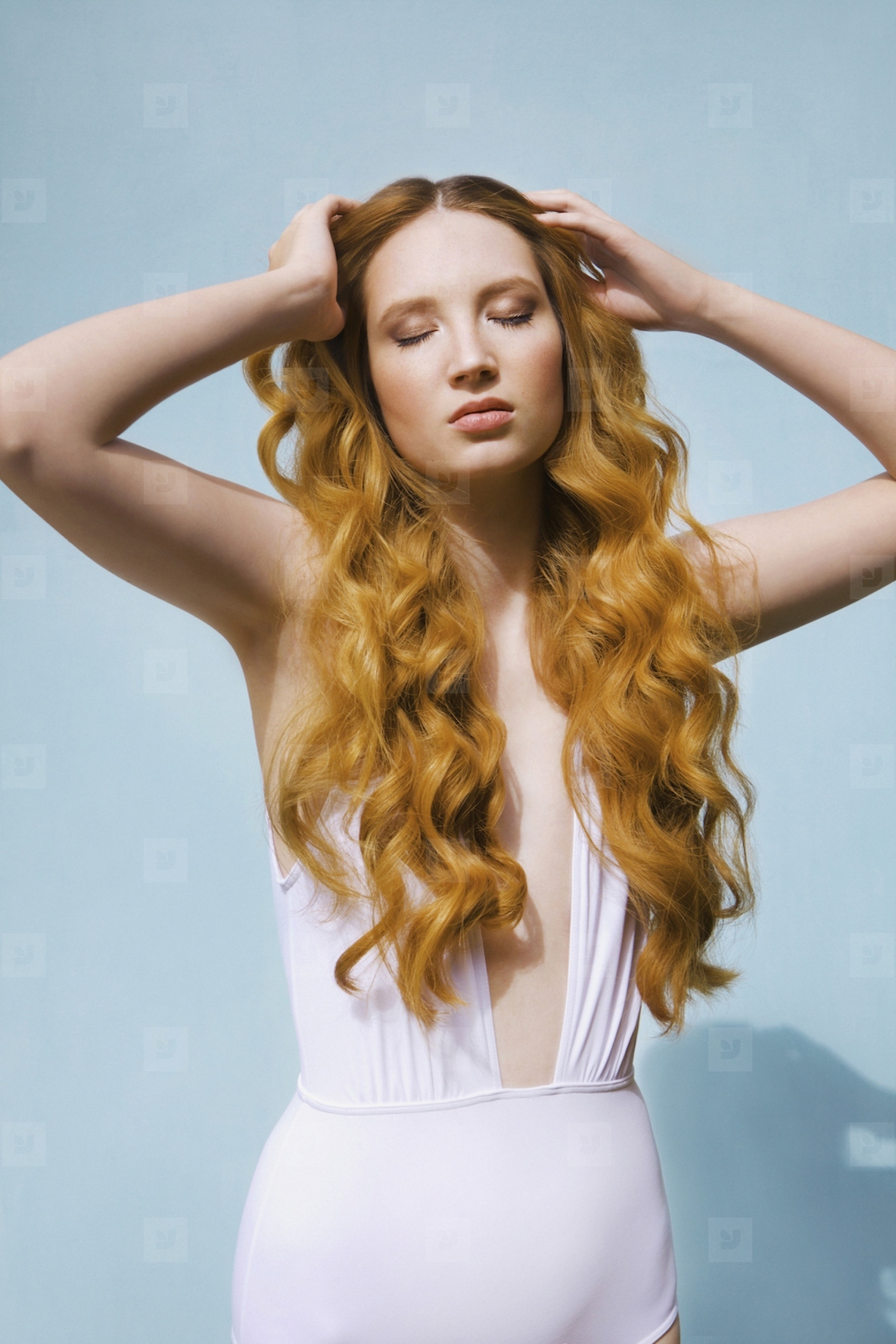 Portrait of beautiful serene young woman with hands in curly