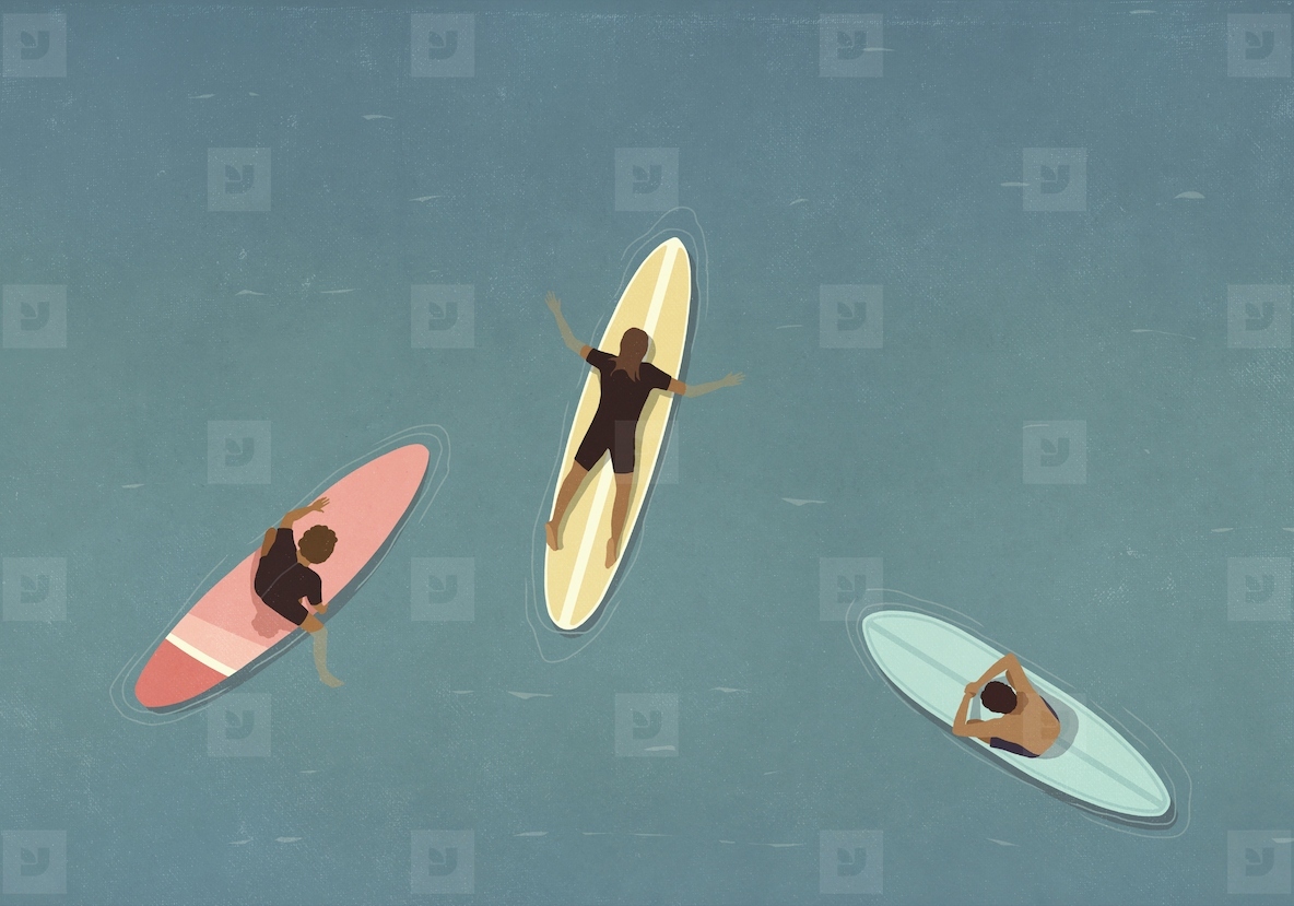 View from above of surfers laying on surfboards in ocean