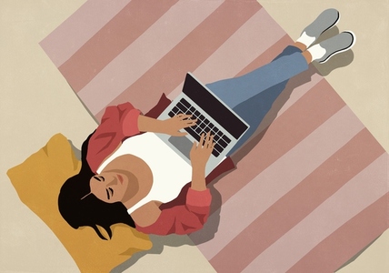View from above of young woman sitting on rug using laptop