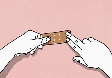 Point of view from above of hands placing bandage on pink background