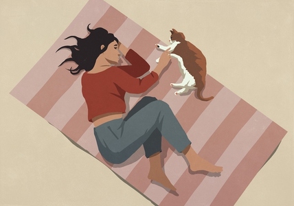 View from above of serene young woman laying on rug and petting cat