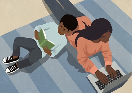 View from above son reading book leaning on mother working at laptop on rug