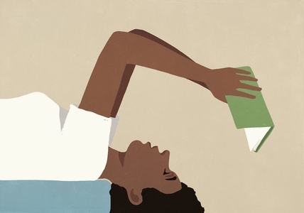 Woman hanging over edge of bed reading book upside down