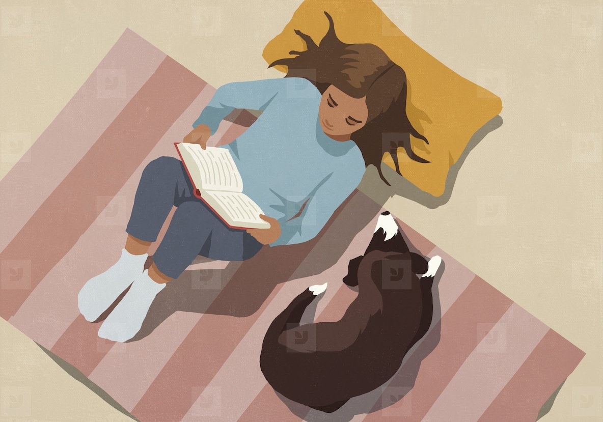 View from above of woman relaxing reading book next to dog on striped rug at home